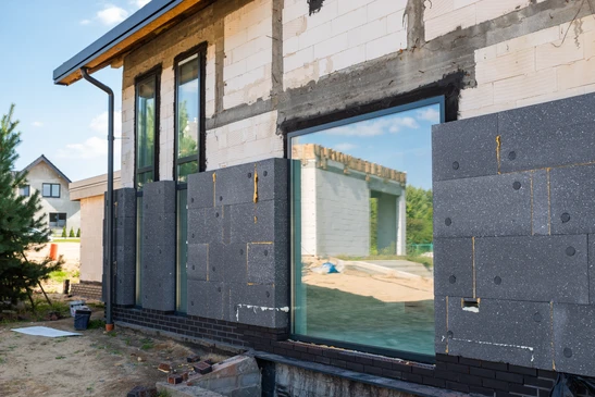 Ouvrier en équipement de protection appliquant un isolant thermique sur façade extérieure